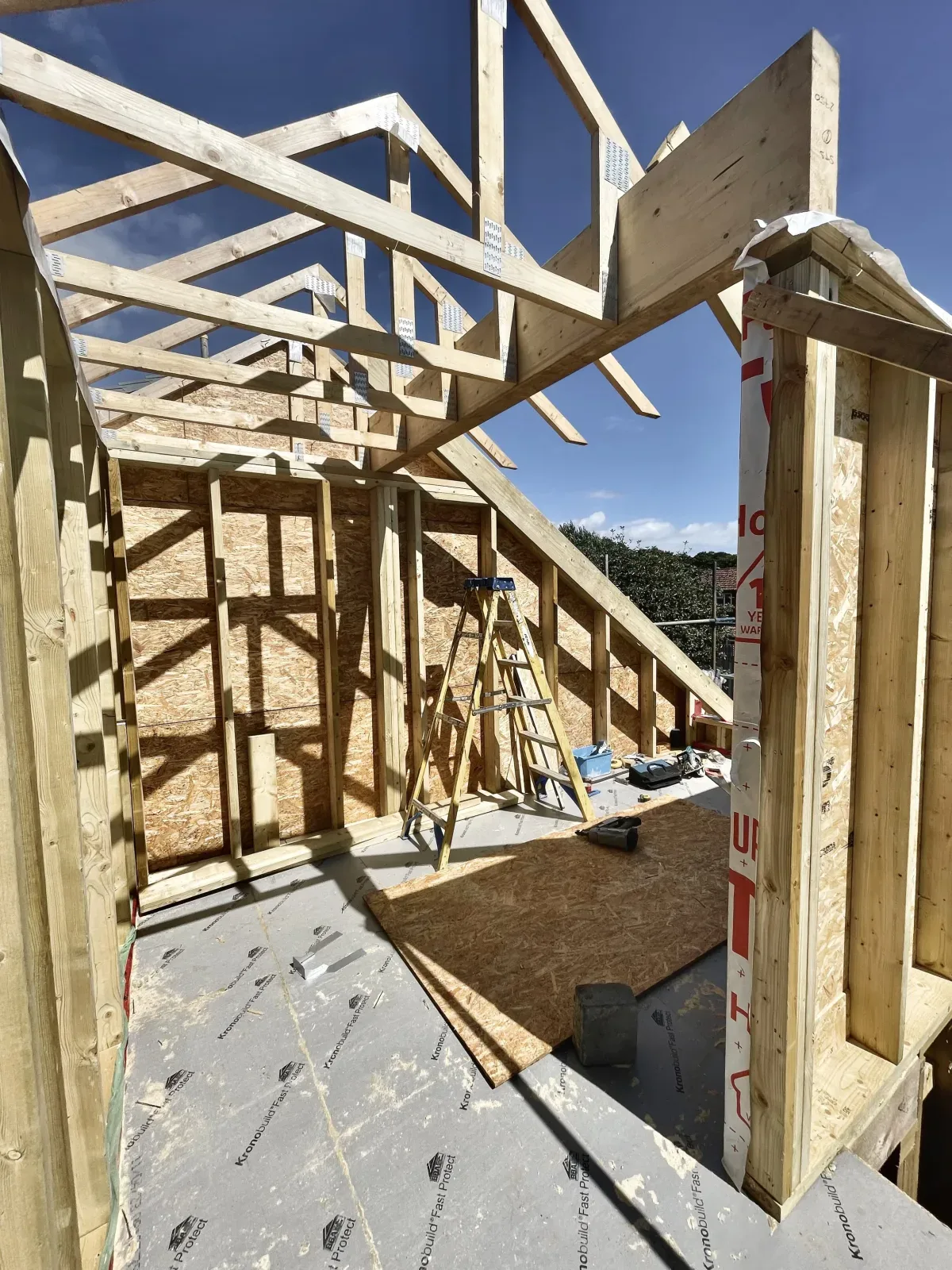 Dormer loft conversion at the framing stage, with new roof trusses against a blue sky in Dorset